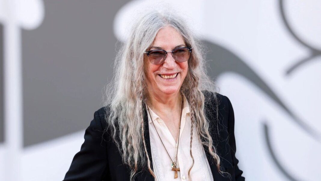Patti Smith en concierto, con micrófono y guitarra