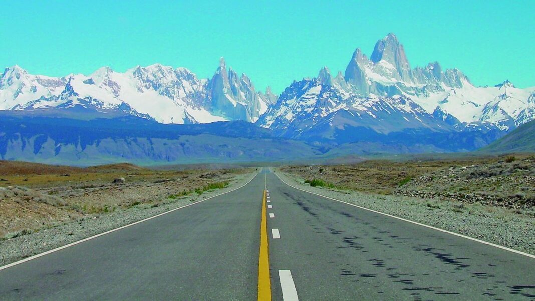Persona consultando un celular frente a un mostrador de aeropuerto o agencia de viajes.
