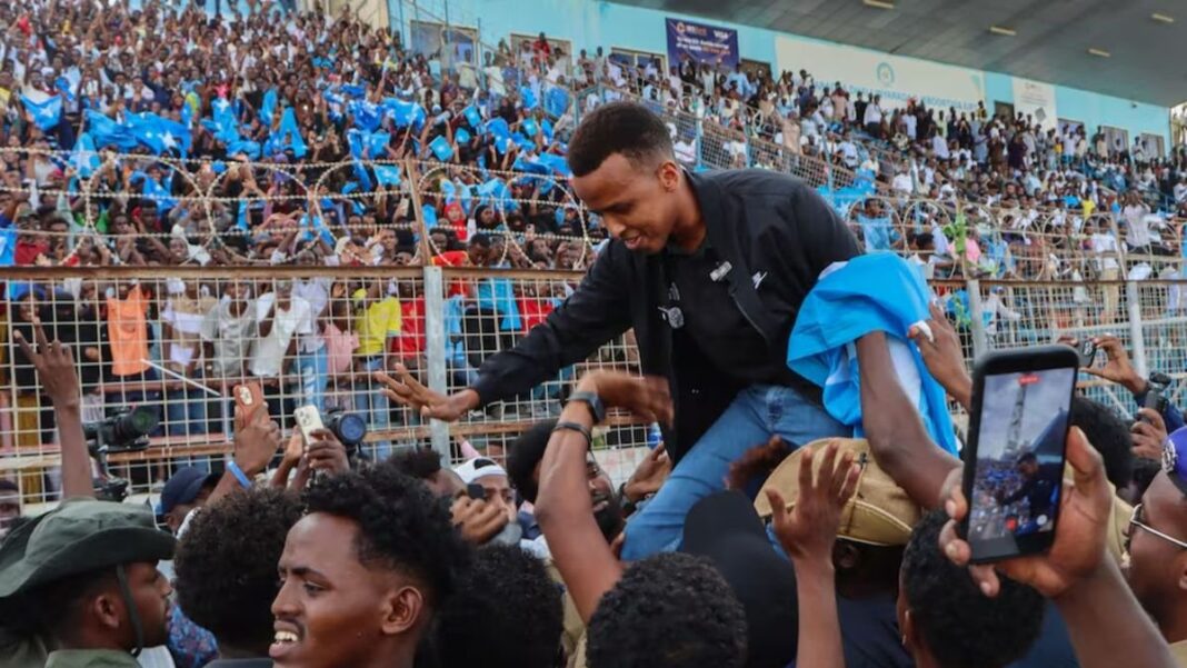 Omar Abdulkadir Artan con uniforme de la Fifa y bandera somalí en el aeropuerto de Mogadiscio