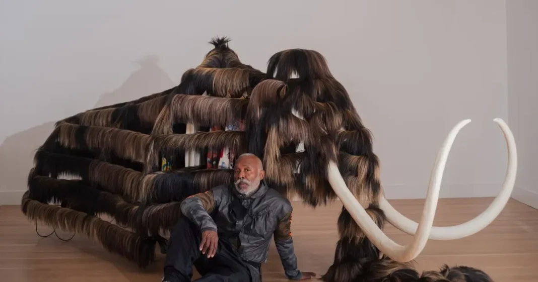 Vista de la instalación 'Mammoth' de Nick Cave en el Museo Smithsonian de Arte Americano, con una mesa de más de veinte metros cubierta de objetos y plataformas con cráneos de mamut.