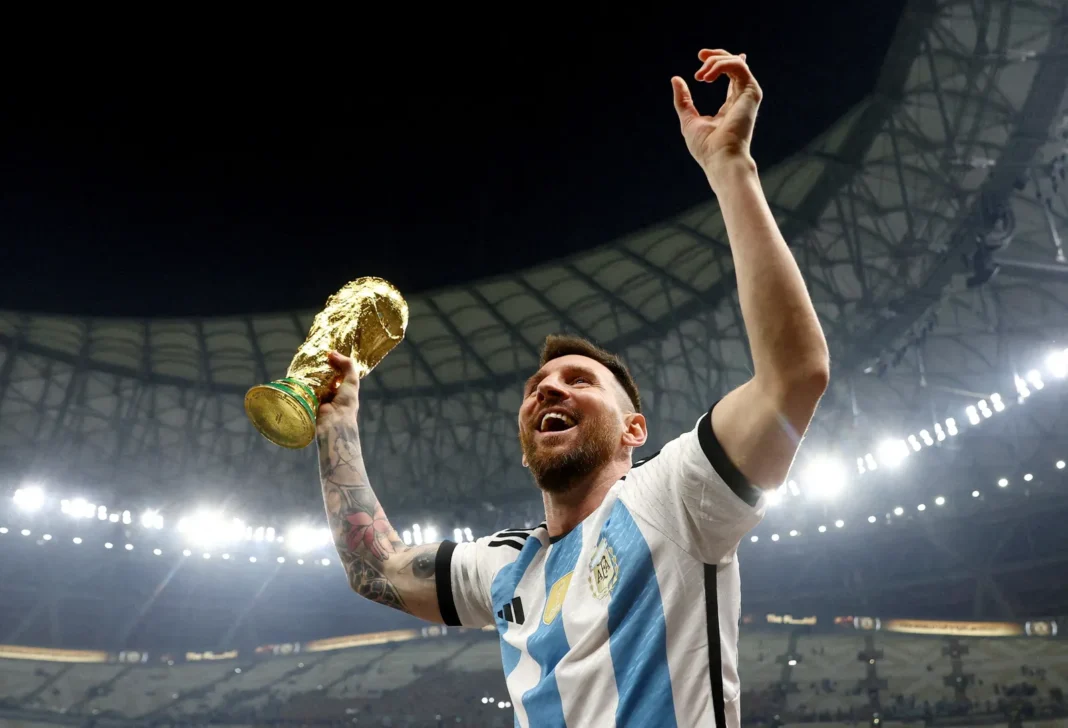 Réplica de la Copa del Mundo que será subastada por Richmond Auctions, junto a una tarjeta coleccionable de Lionel Messi